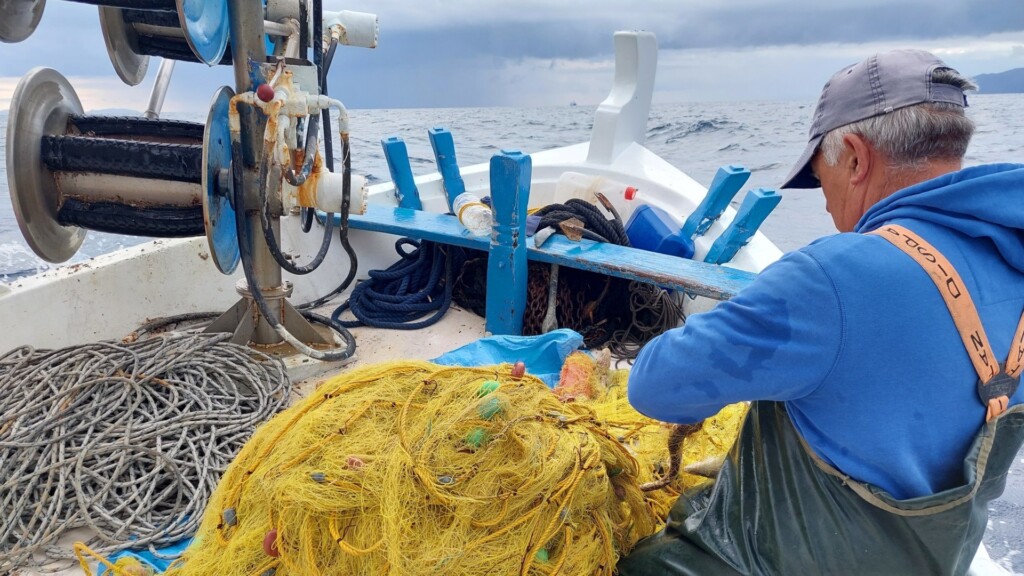 small scale fisher on boat fishing net greece